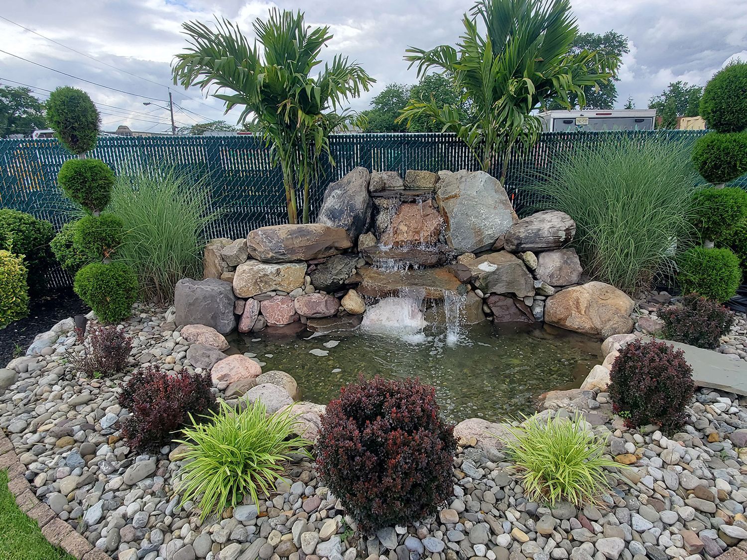 There is a waterfall in the middle of the garden surrounded by rocks and plants.