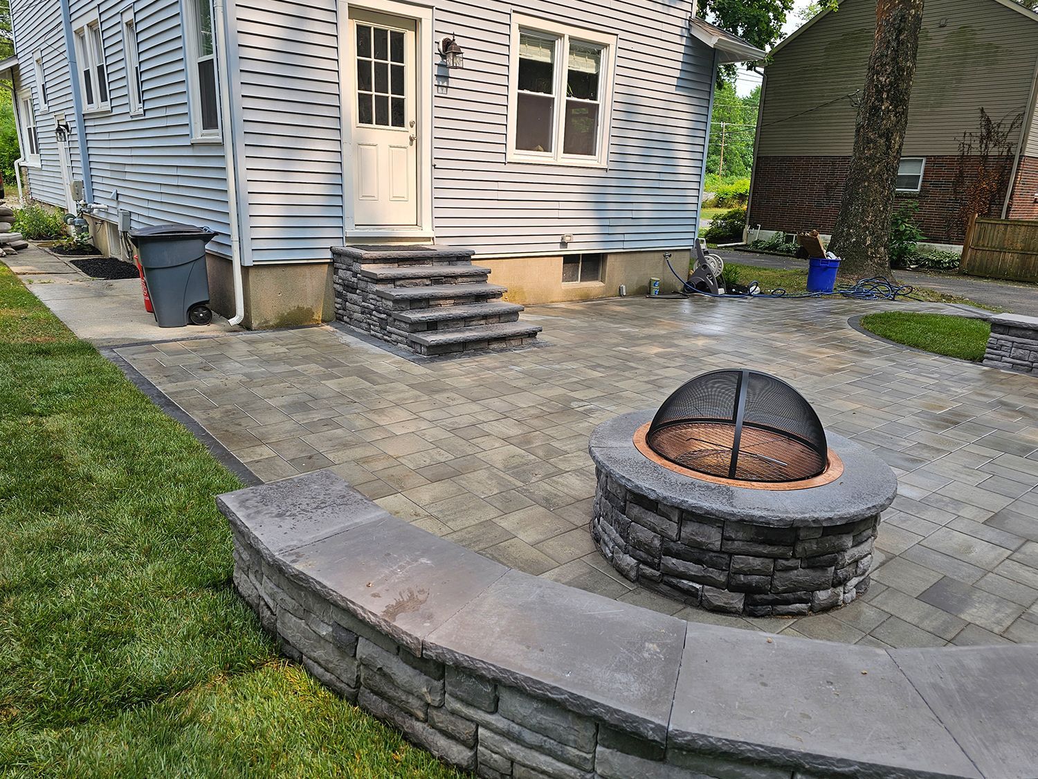 A fire pit is sitting on a patio in front of a house.