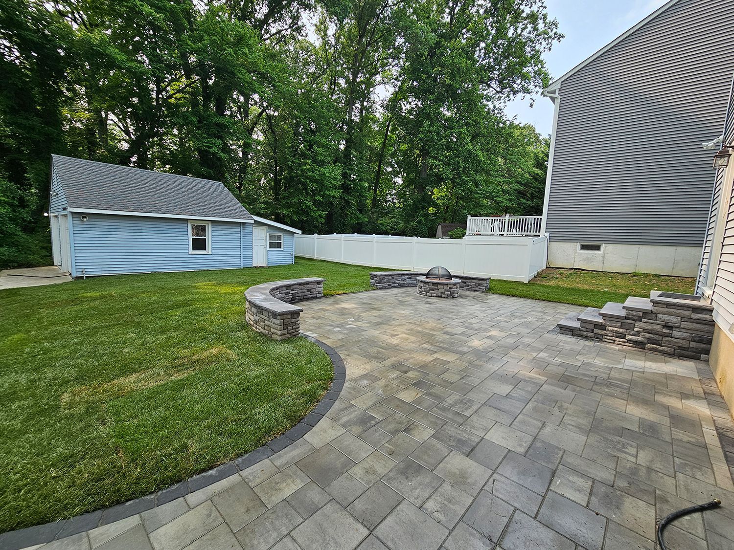 A patio with a fire pit in the backyard of a house.