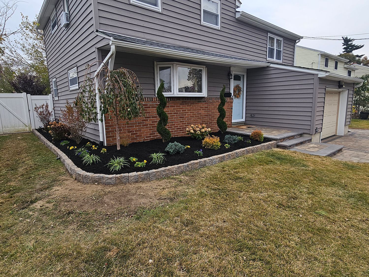 A house with a lush green lawn and a garden in front of it.