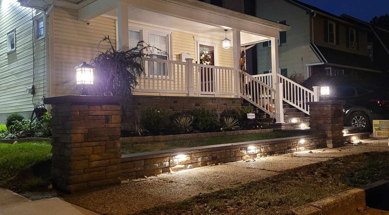 A house with a porch and stairs is lit up at night.