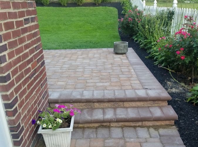 A brick walkway with steps leading up to a lawn