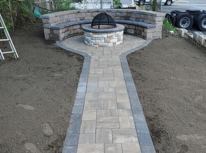 A stone walkway with a fire pit in the middle of it.