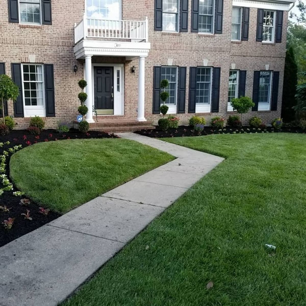 A brick house with black shutters and a walkway leading to it