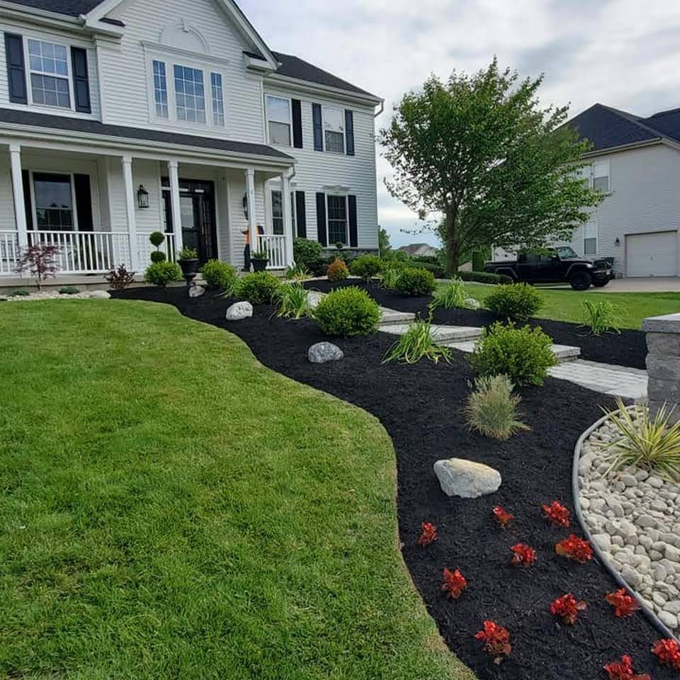 A large white house with a lush green lawn and a black truck parked in front of it.