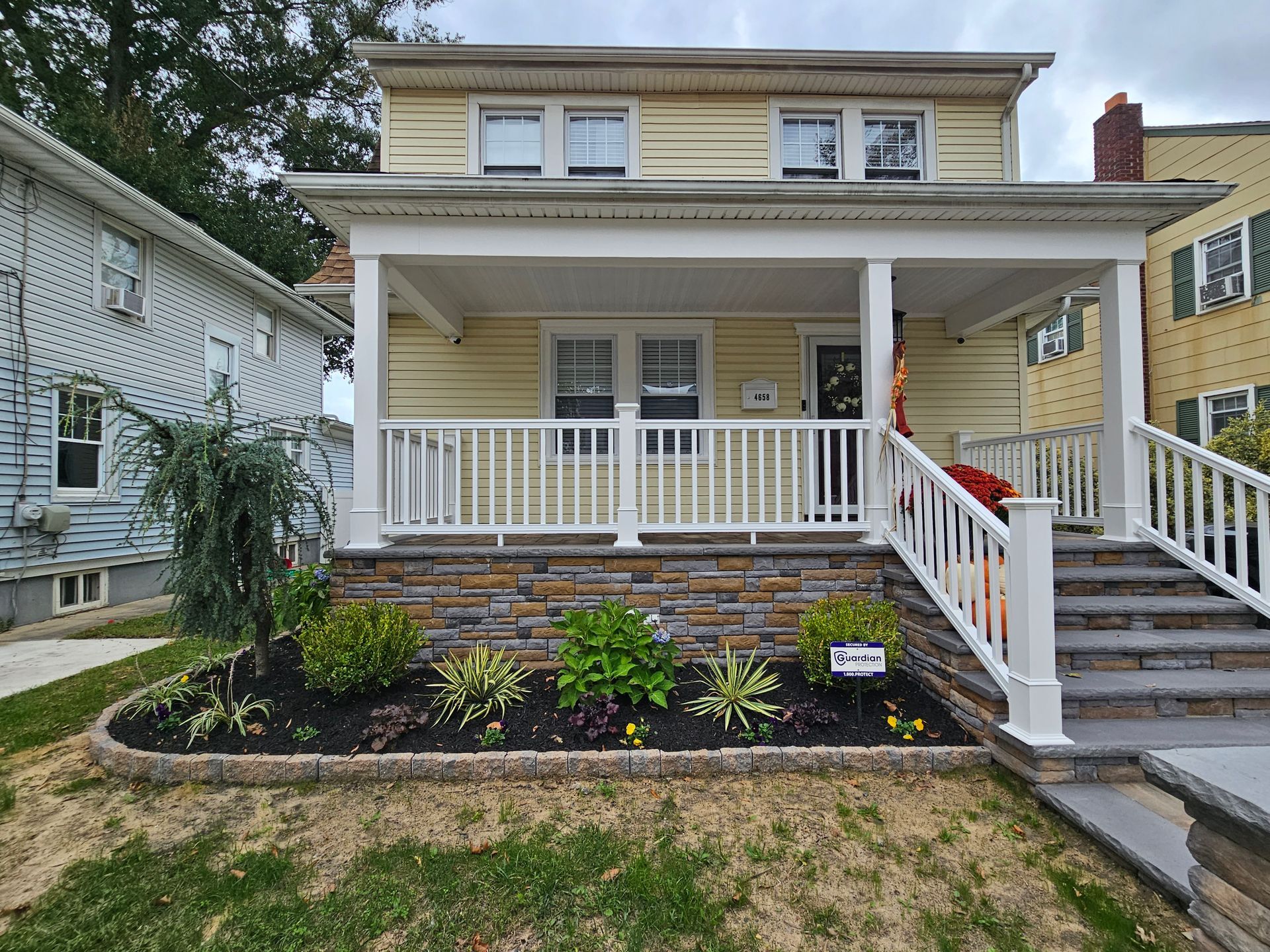 A yellow house with a white porch and stairs