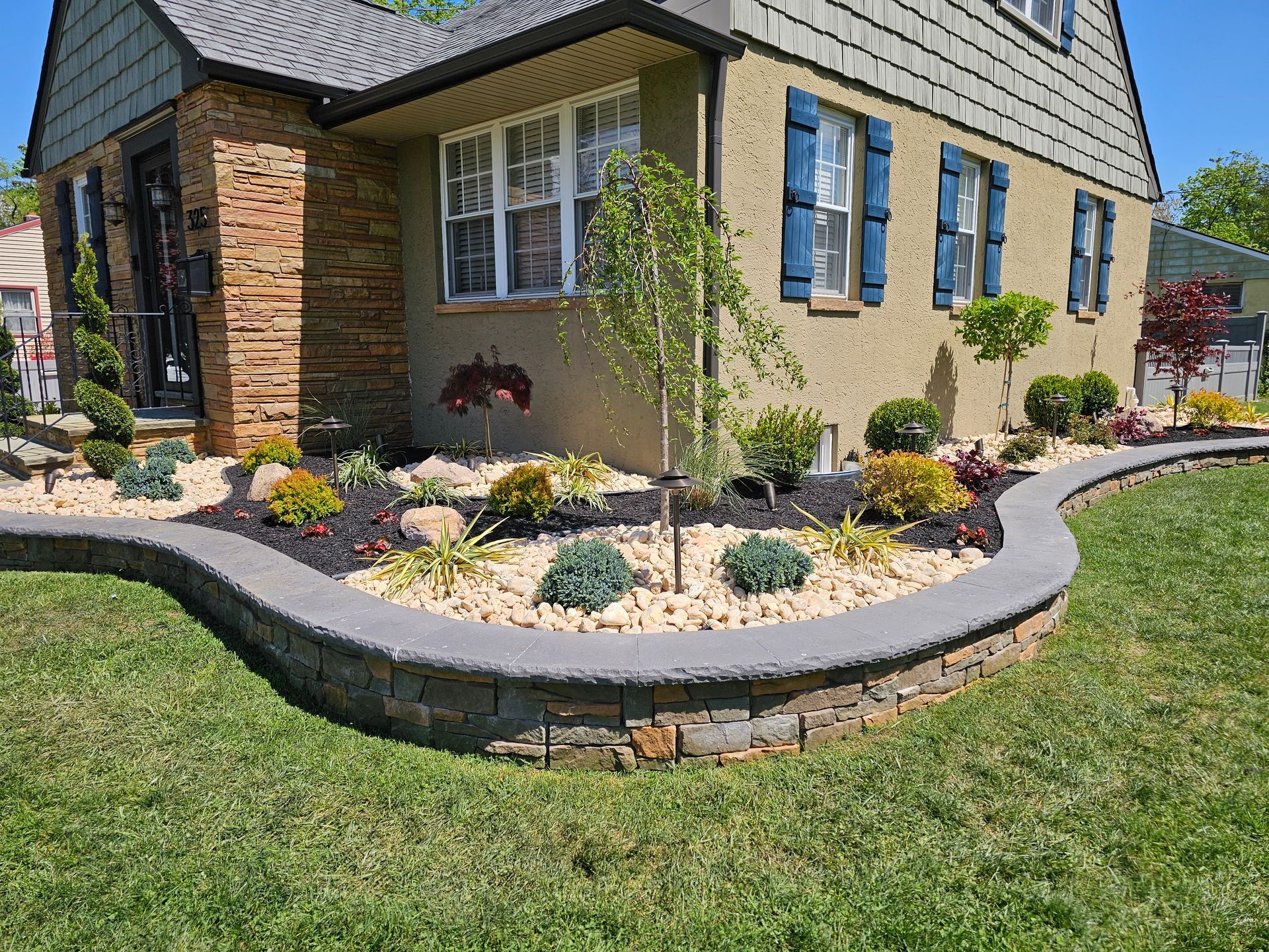 A house with a lush green lawn and a garden in front of it.