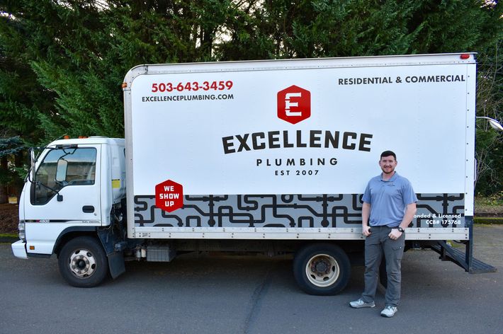 A man standing next to a white box truck for Excellence Plumbing.
