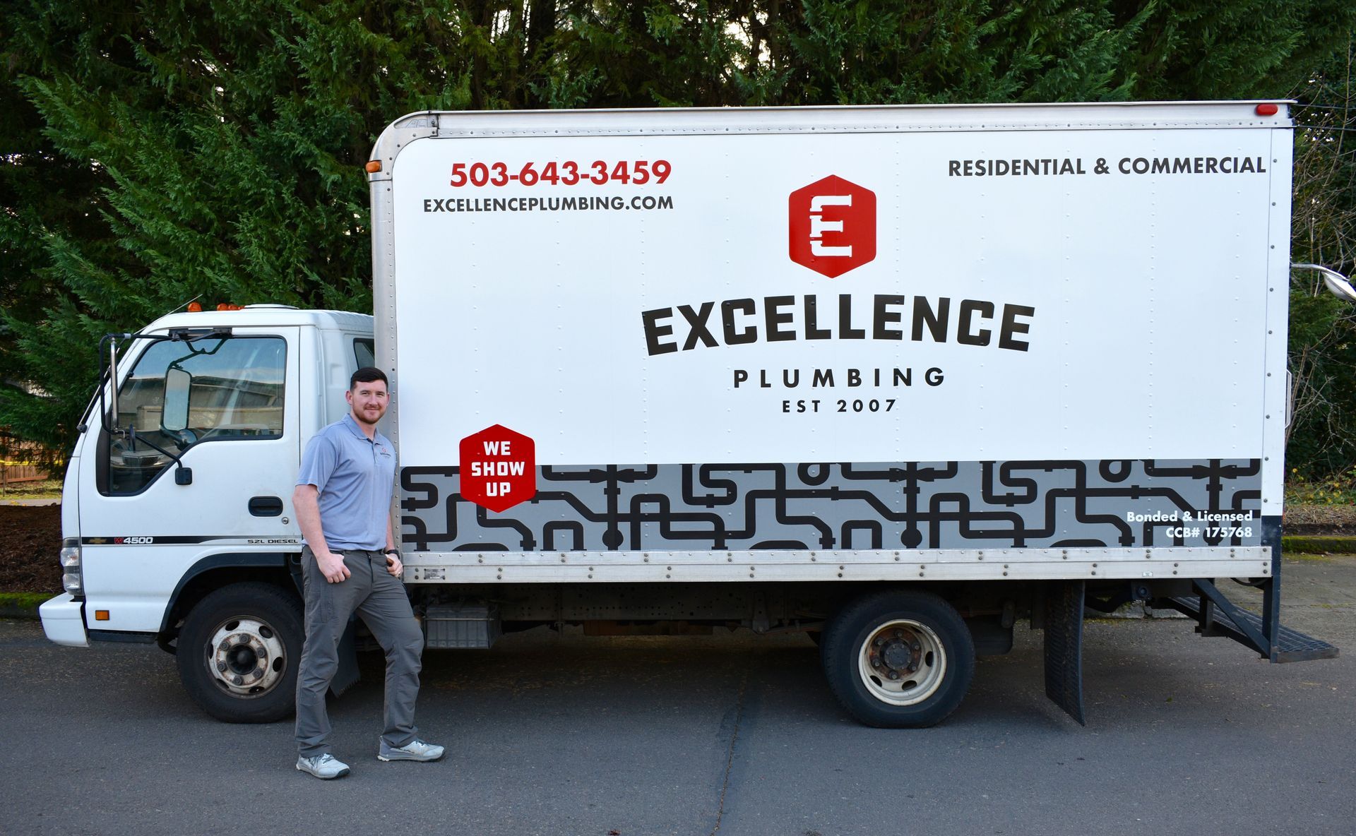 A man standing next to a white plumbing truck with 