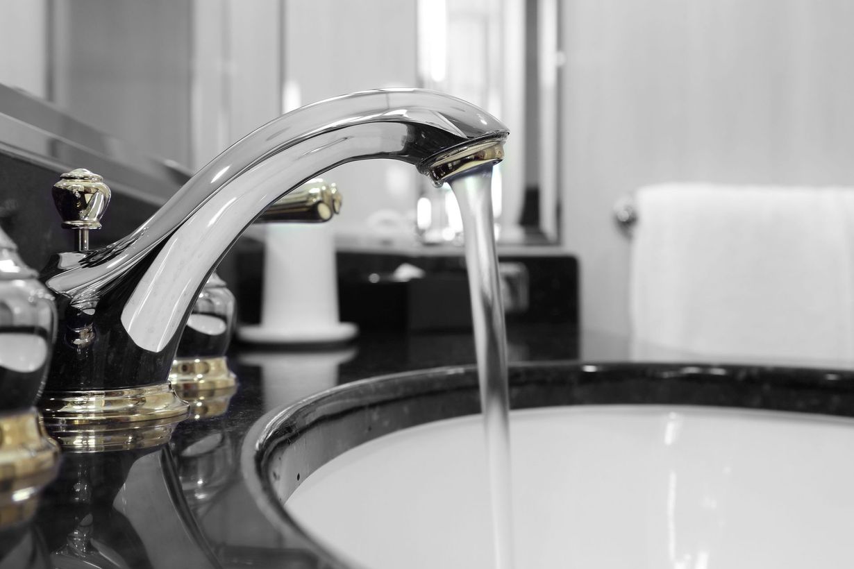 A red wrench and plumbing supplies on a kitchen counter near a double sink.