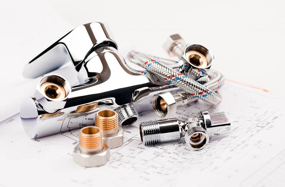 Chrome faucet and plumbing parts on a blueprint background.