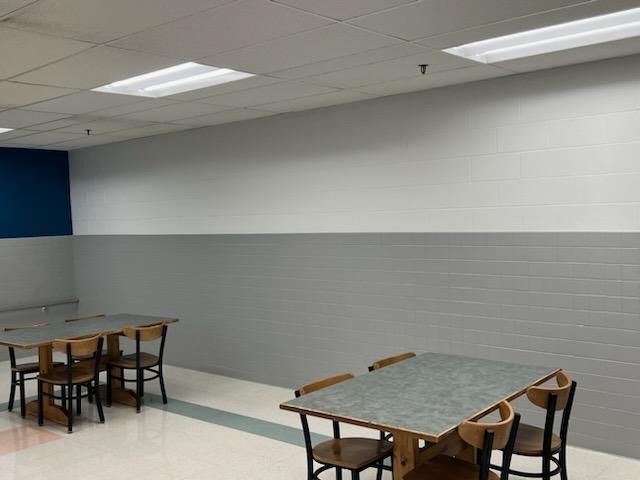 Two tables with chairs in a minimalist break room with a two-toned gray and white block-patterned wall.