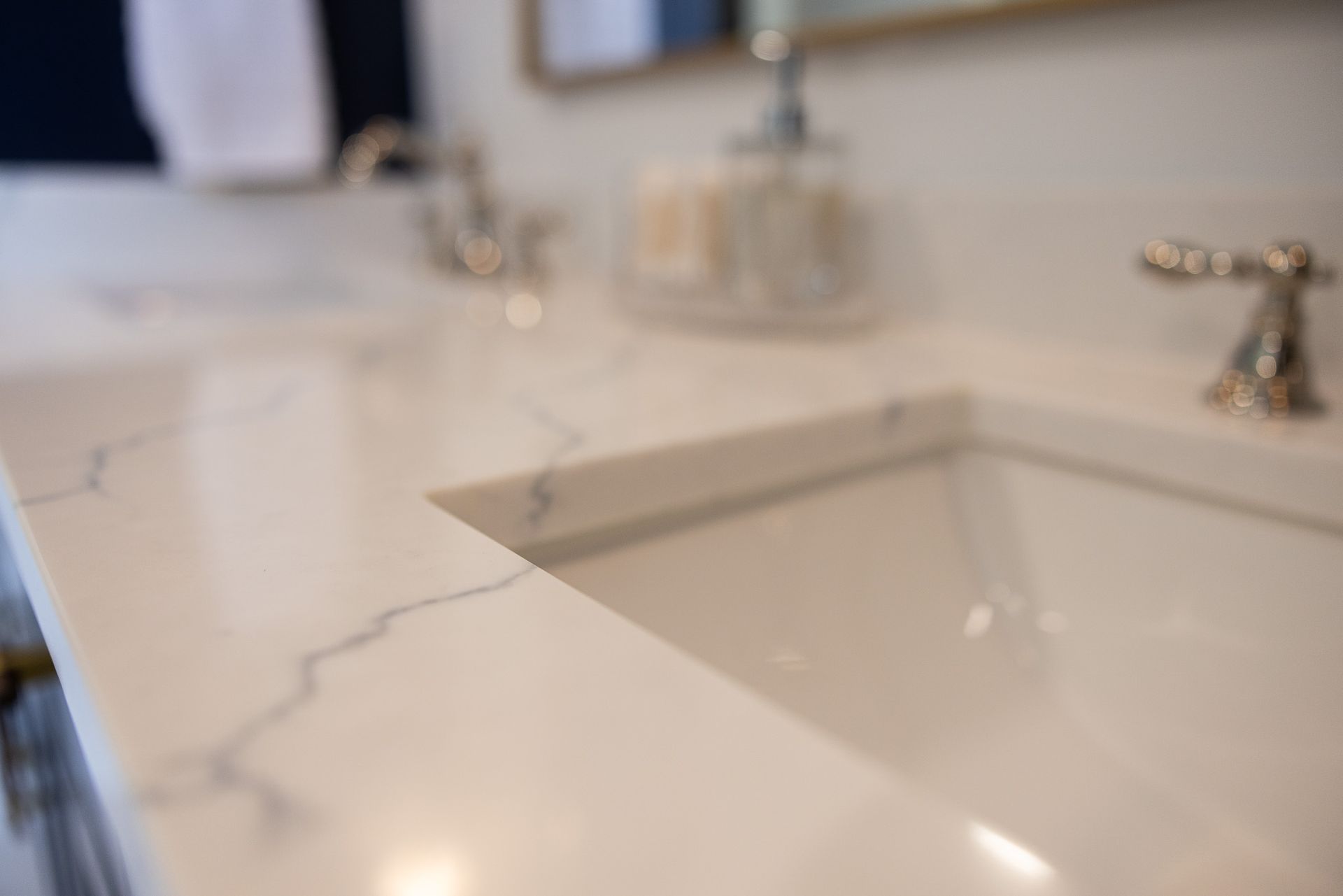 A close-up view of a bathroom vanity with a white marble-patterned countertop and a modern metallic faucet.