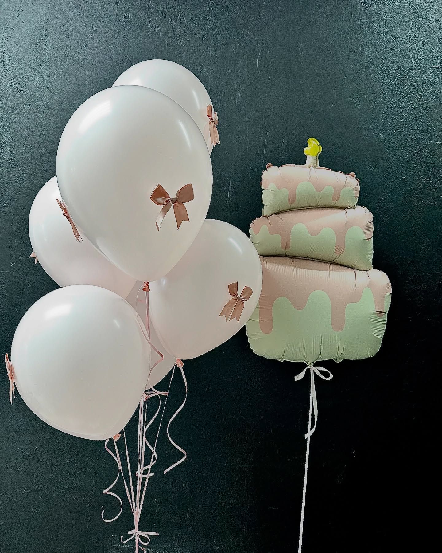 A bunch of pink balloons next to a cake shaped balloon