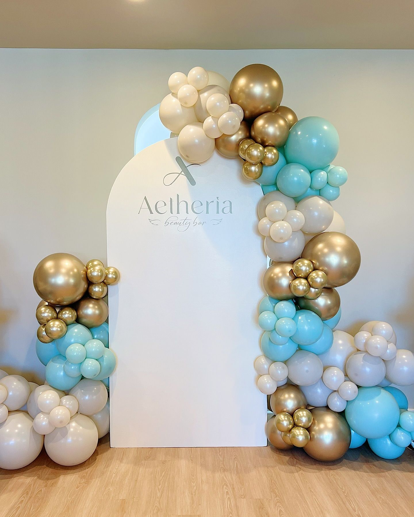 A bunch of balloons are sitting on a wooden floor in front of a white wall.