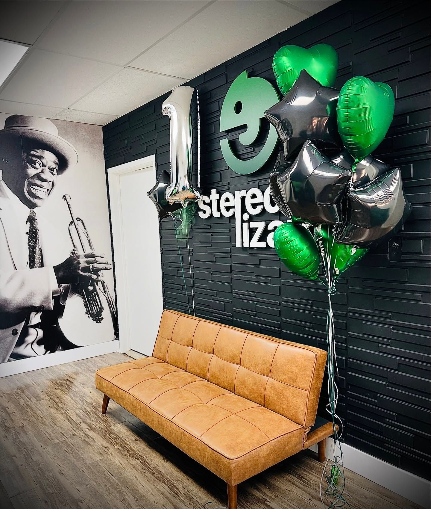 A couch with balloons in front of a wall that says stereo liza