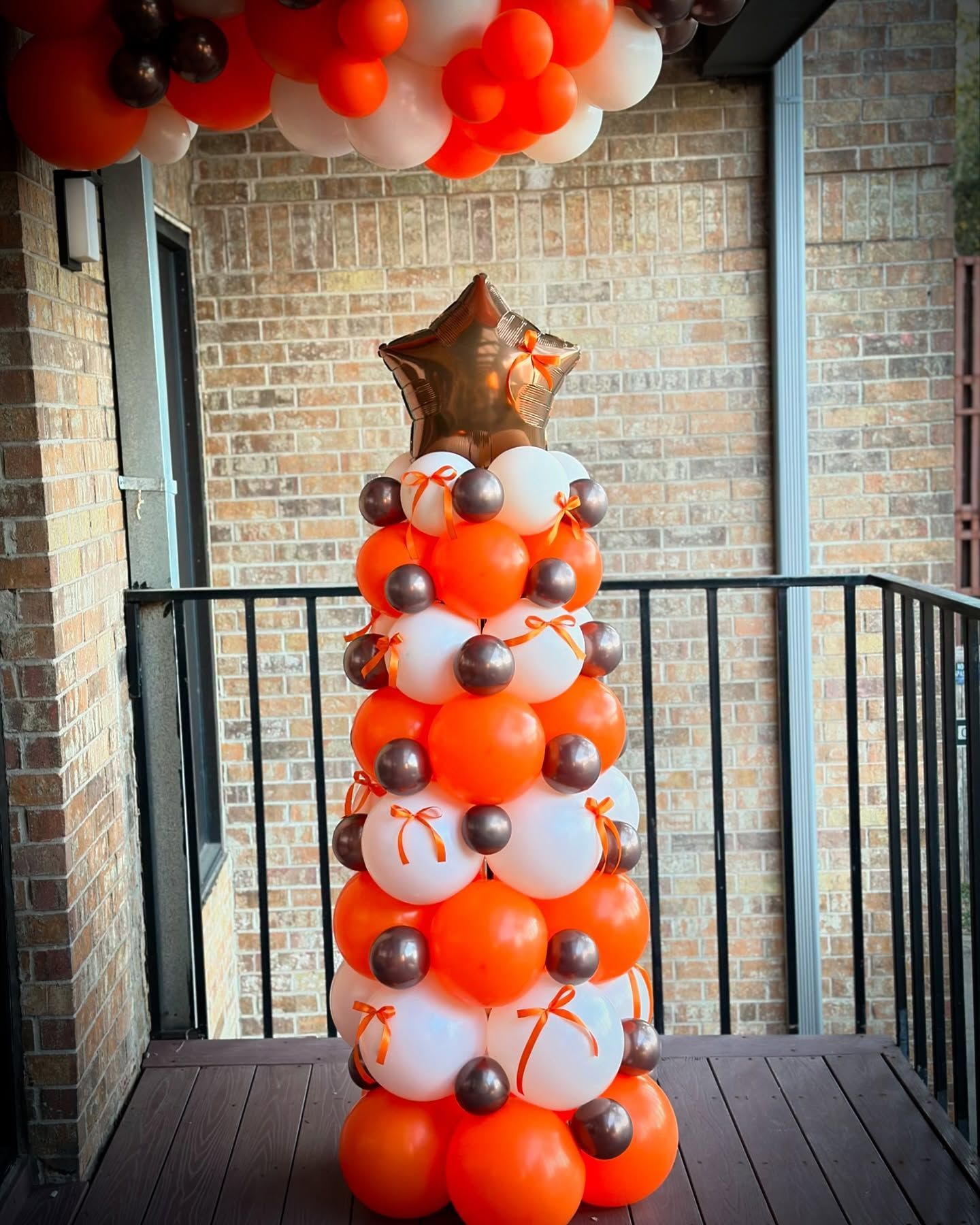 A christmas tree made of orange and white balloons on a balcony.