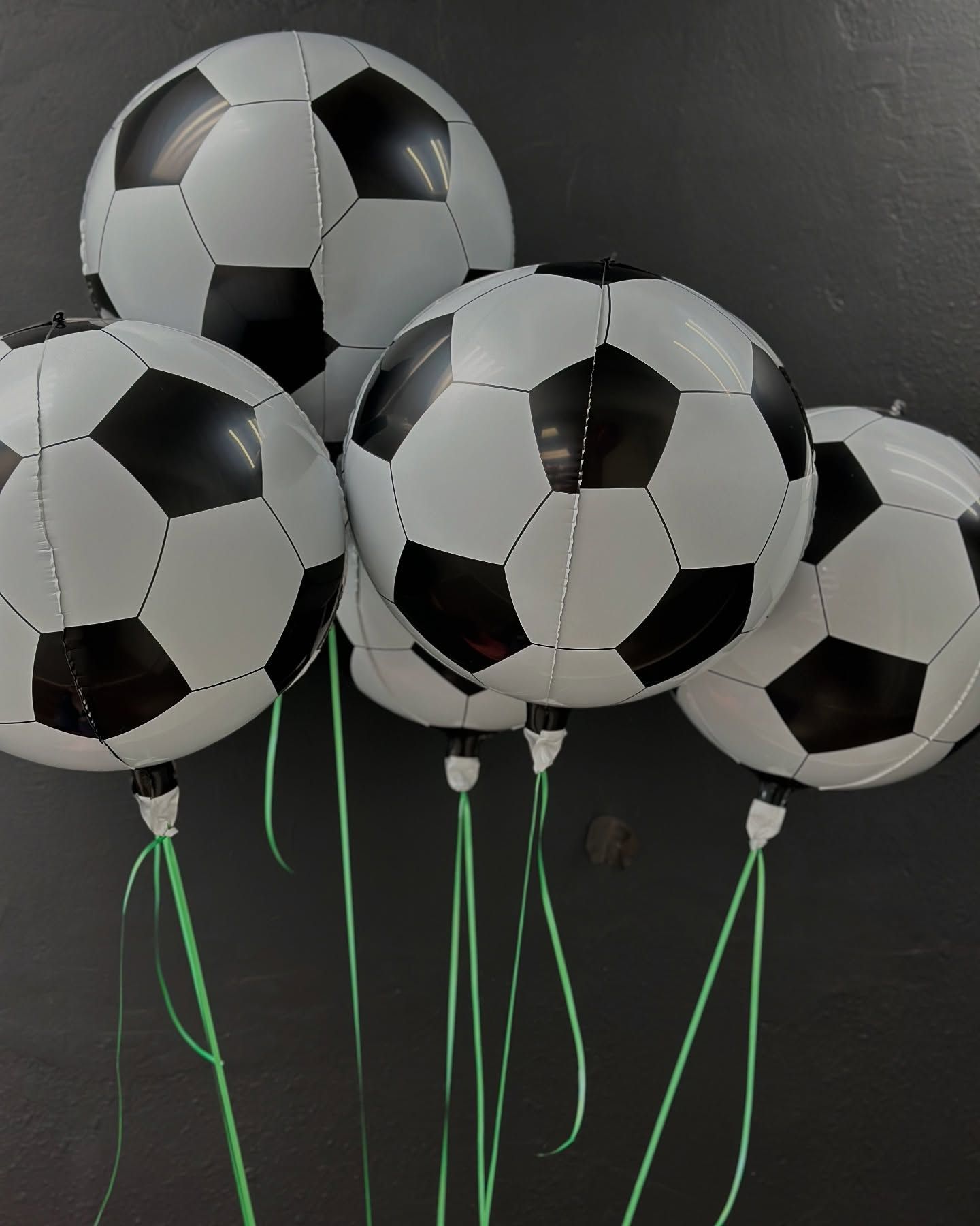 A bunch of soccer balls with green strings attached to them