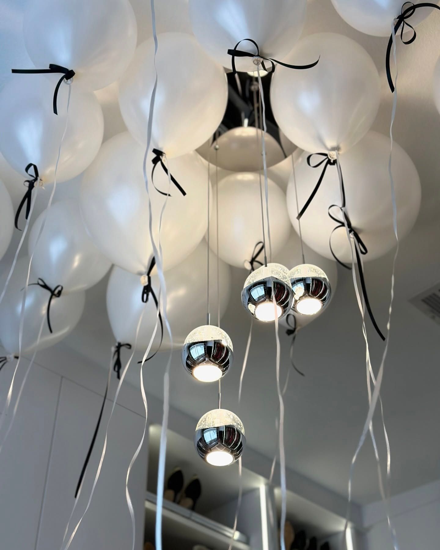 A bunch of white balloons hanging from the ceiling