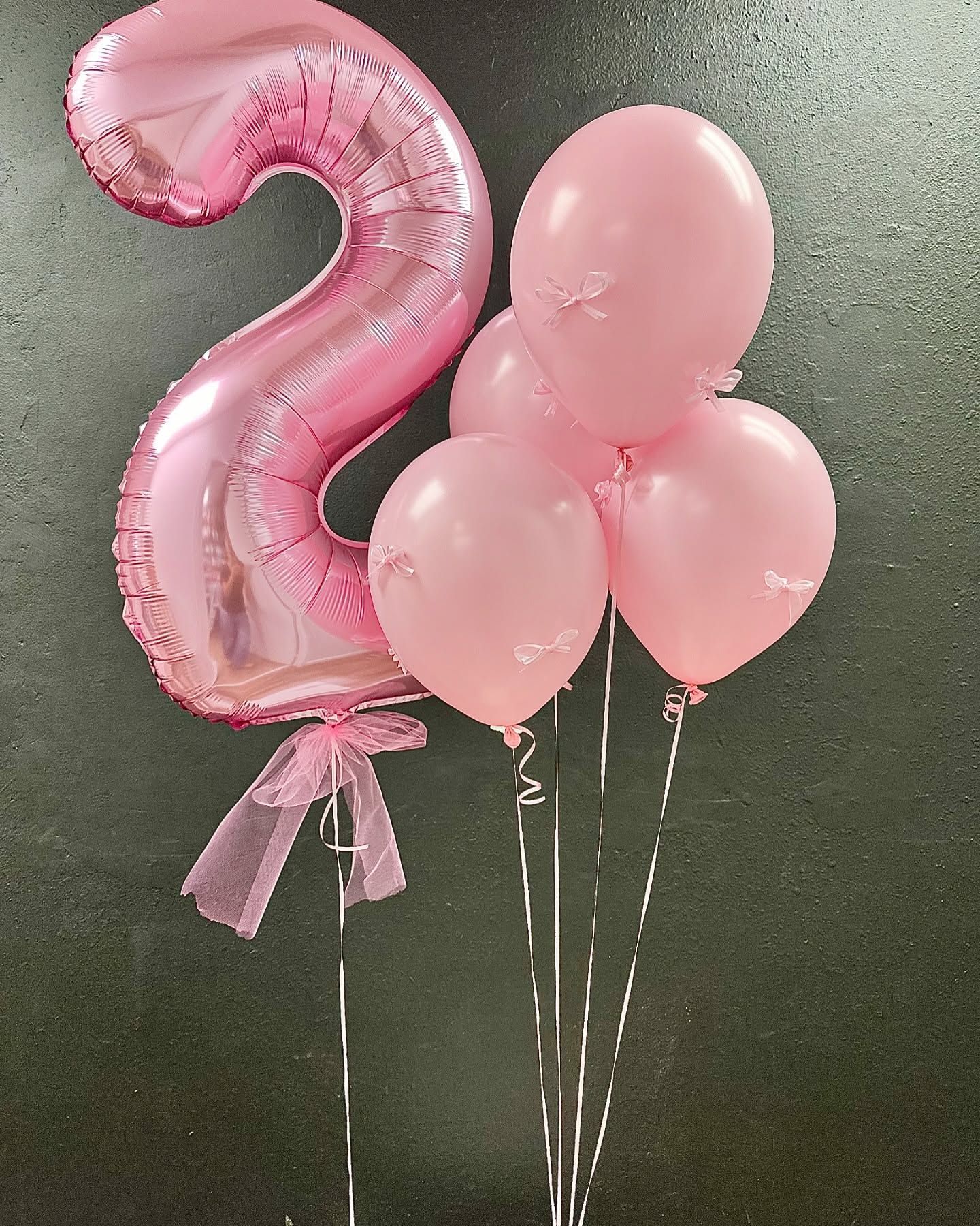 A pink number 2 balloon surrounded by pink balloons
