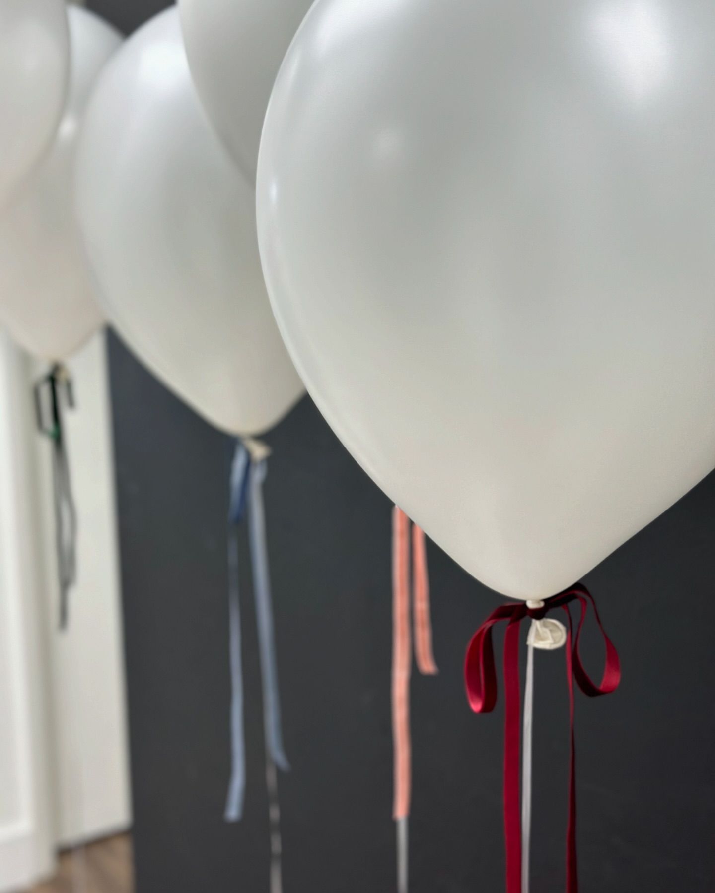 A row of white balloons tied with red ribbons