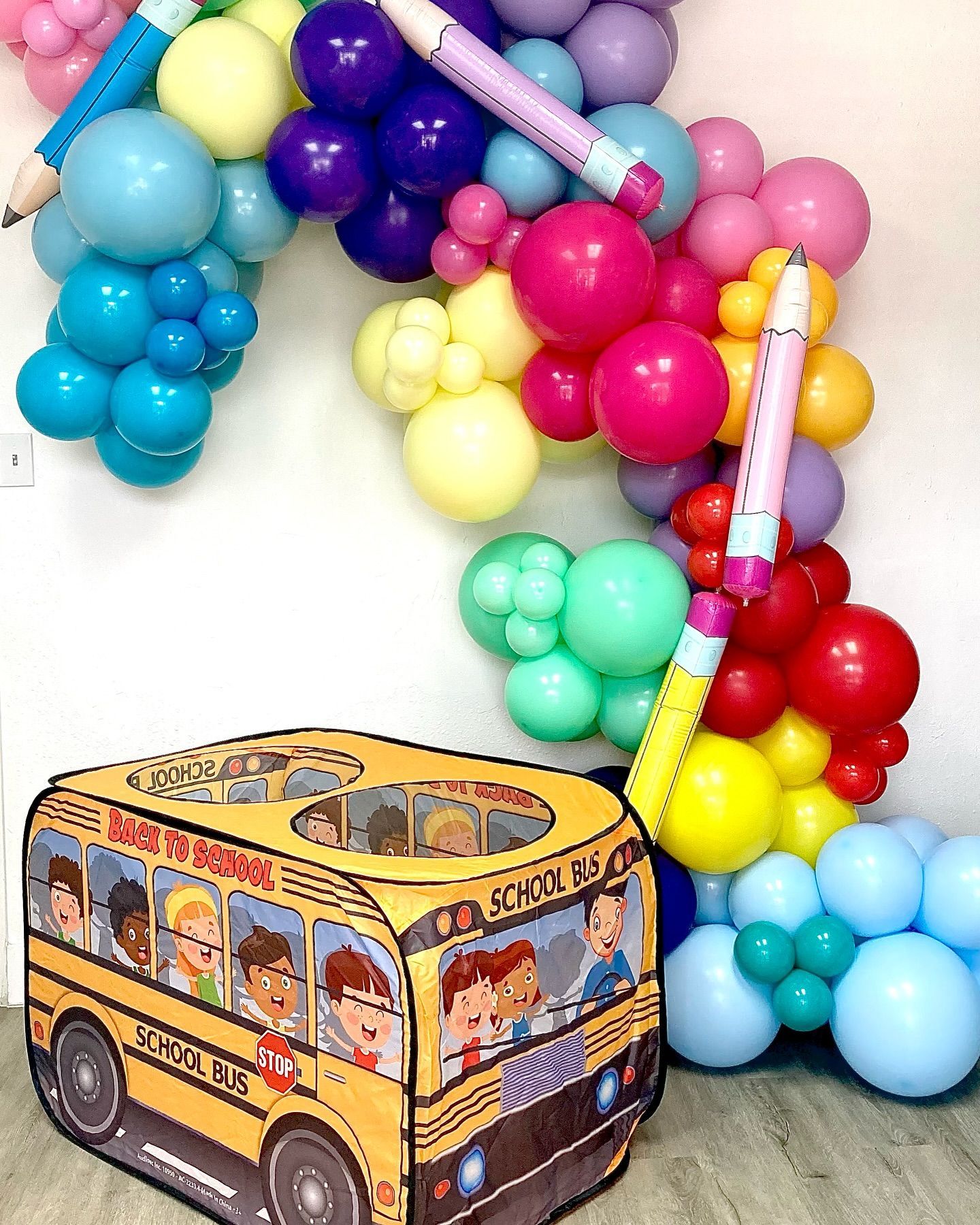 A school bus is surrounded by balloons and pencils