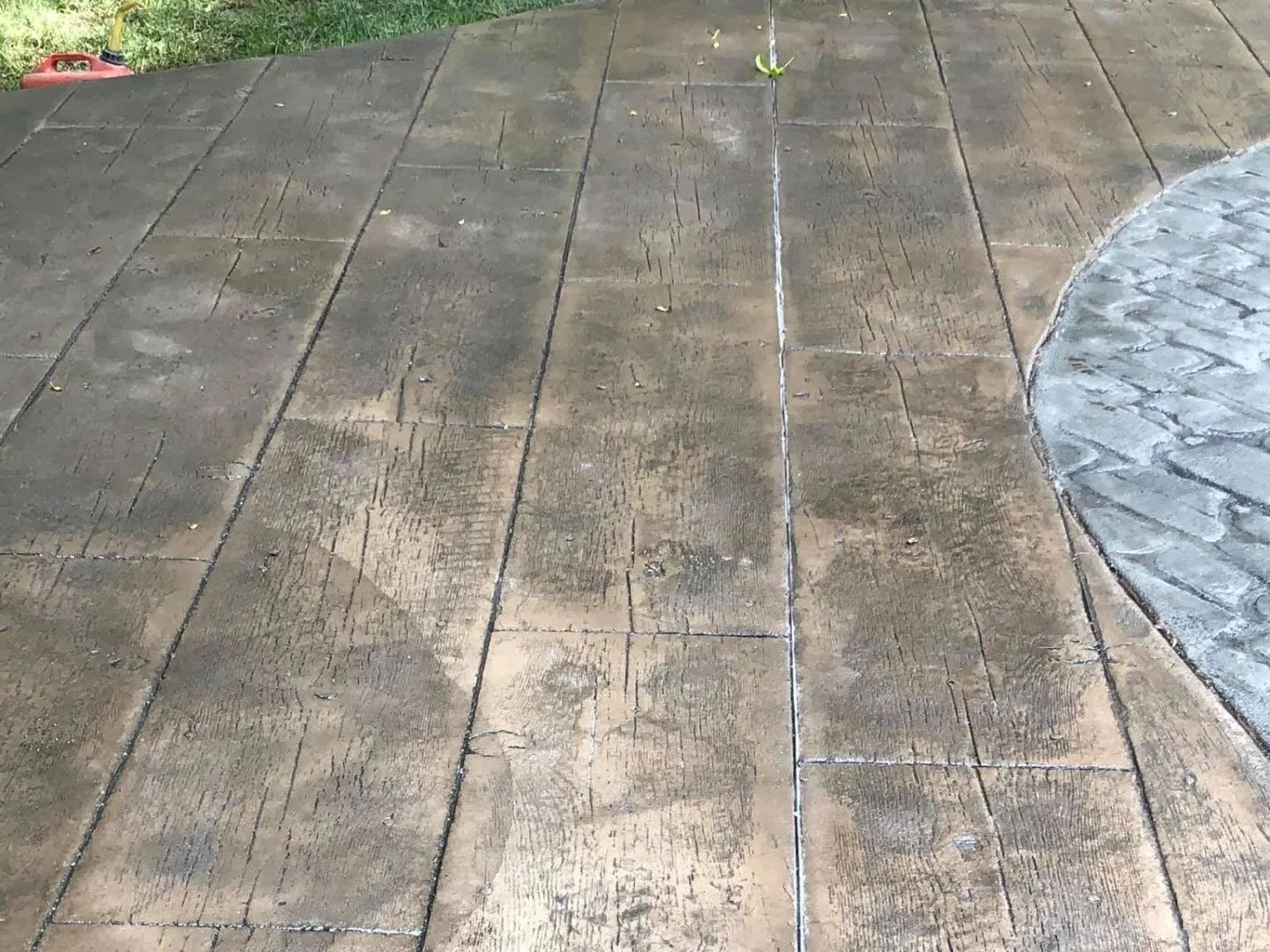 Stamped concrete patio with wood-like texture and a section of stone pavers; brown tones.