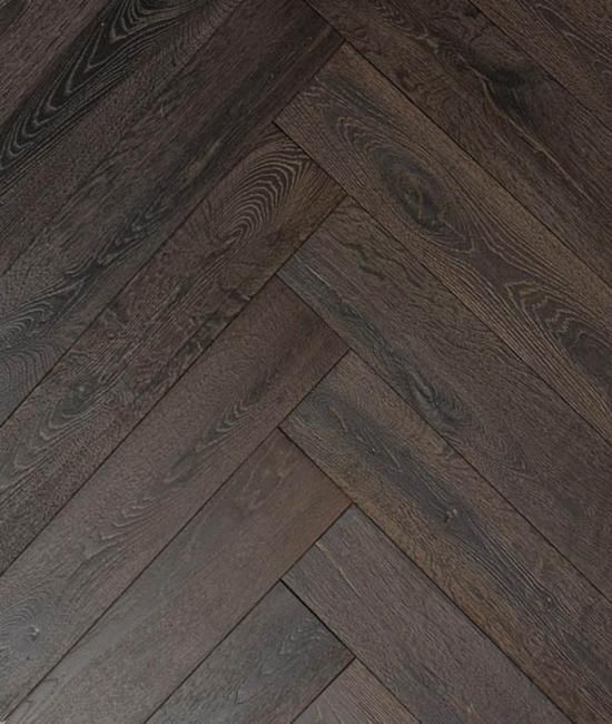 A close up of a wooden floor in a herringbone pattern.