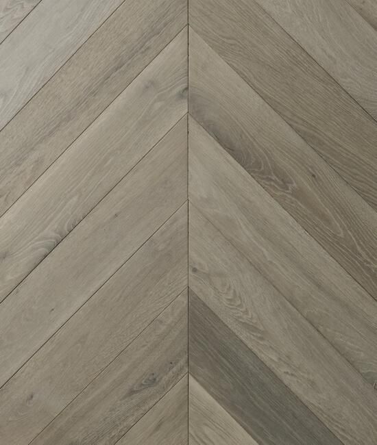 A close up of a wooden floor with a chevron pattern.