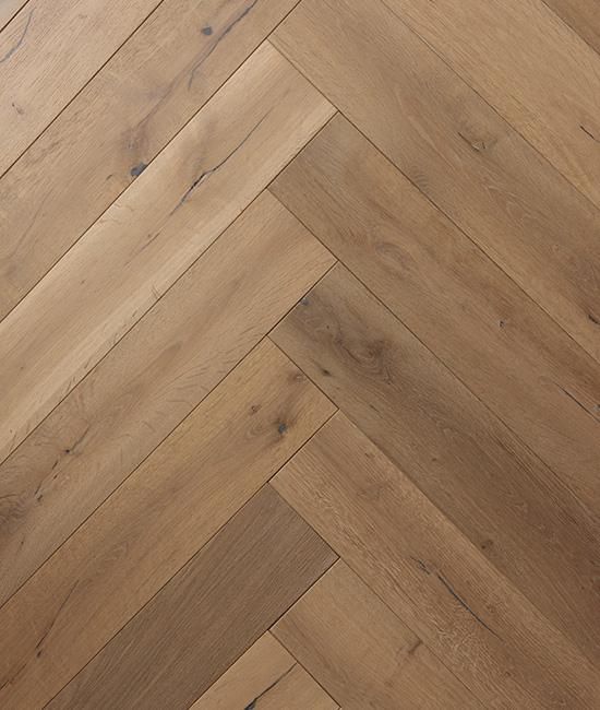 A close up of a wooden floor in a herringbone pattern.