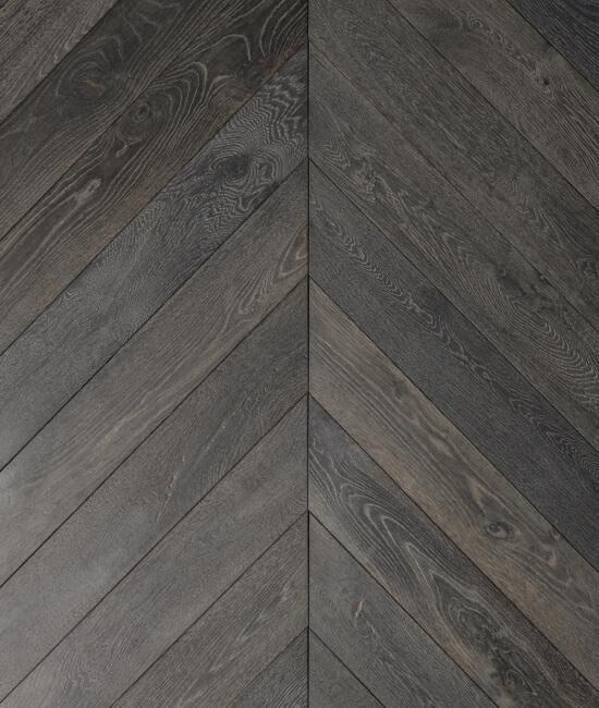 A close up of a gray wooden floor with a chevron pattern.