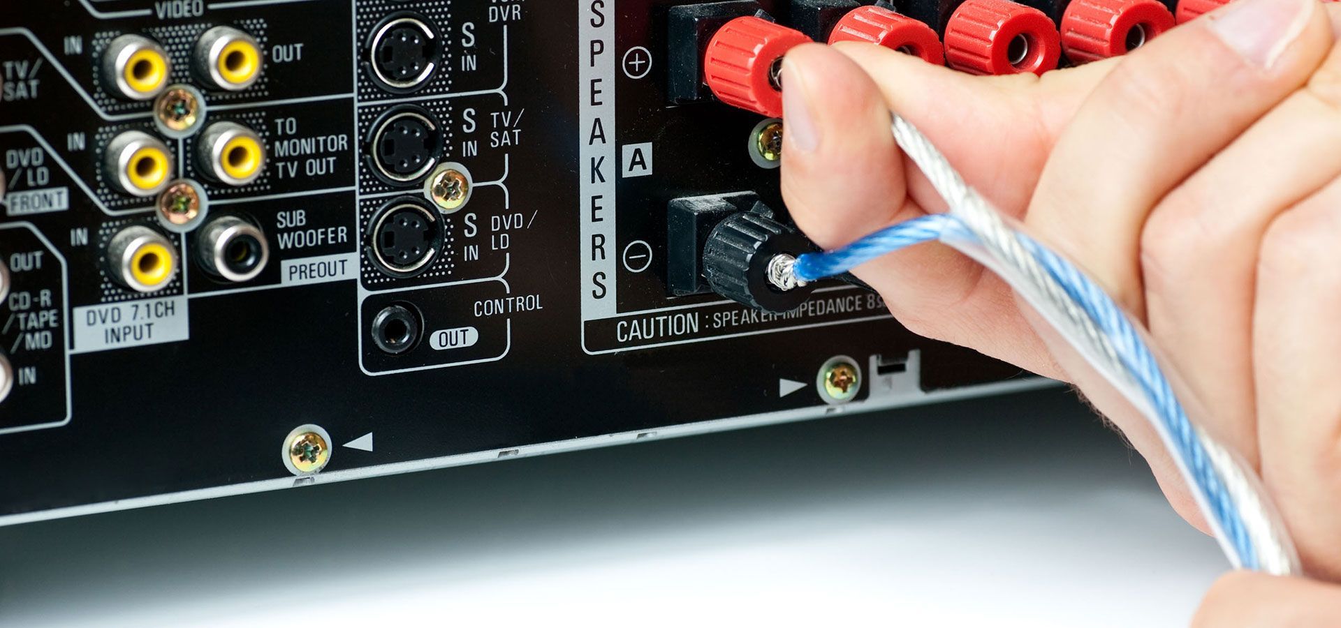 Hand plugging blue cable into red and black audio/video input jacks on a stereo panel