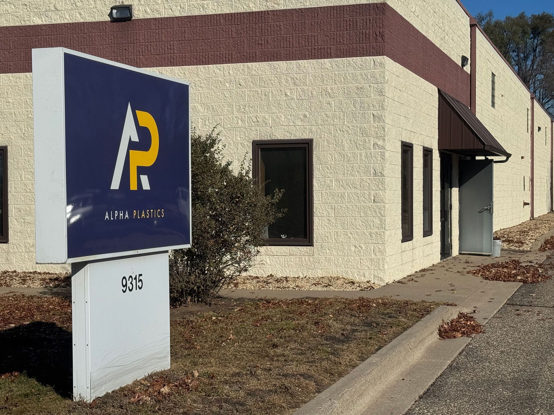 A building with a sign in front of Alpha Plastics