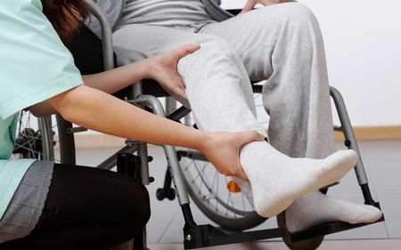 A woman in a wheelchair is being helped by a nurse.