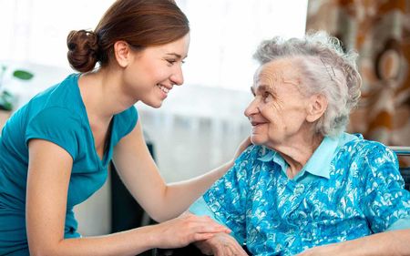 A young woman is talking to an older woman in a wheelchair.