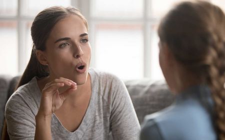 A woman is talking to another woman while sitting on a couch.