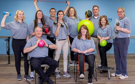 A group of people are posing for a picture in a gym with exercise equipment.