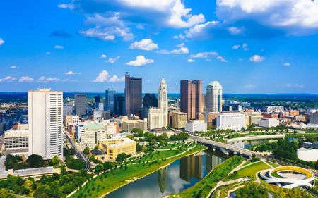 An aerial view of a city skyline with a river in the foreground.