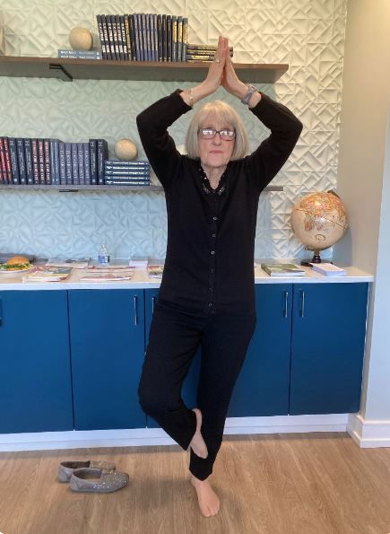 A woman is standing in a yoga pose in a kitchen.