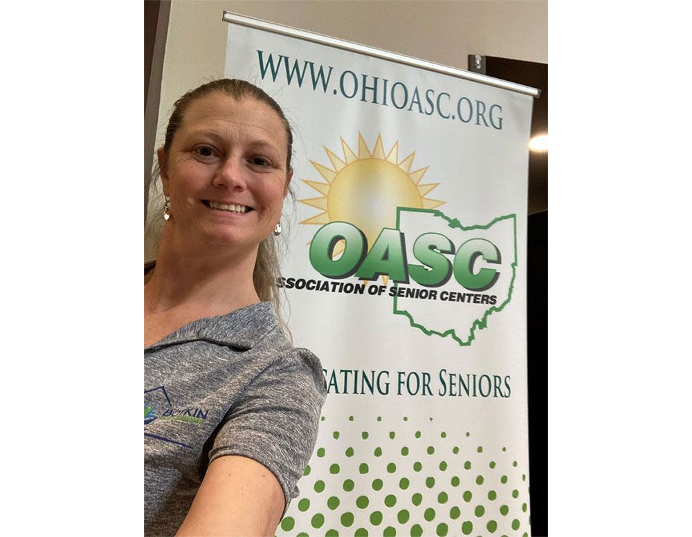 A woman is standing in front of a oasc banner.