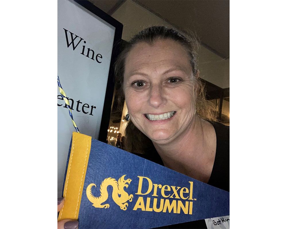 A woman is holding a flag that says drexel alumni