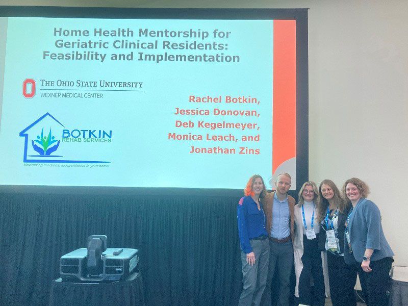 A group of people standing in front of a screen that says home health mentorship for geriatric clinical residents