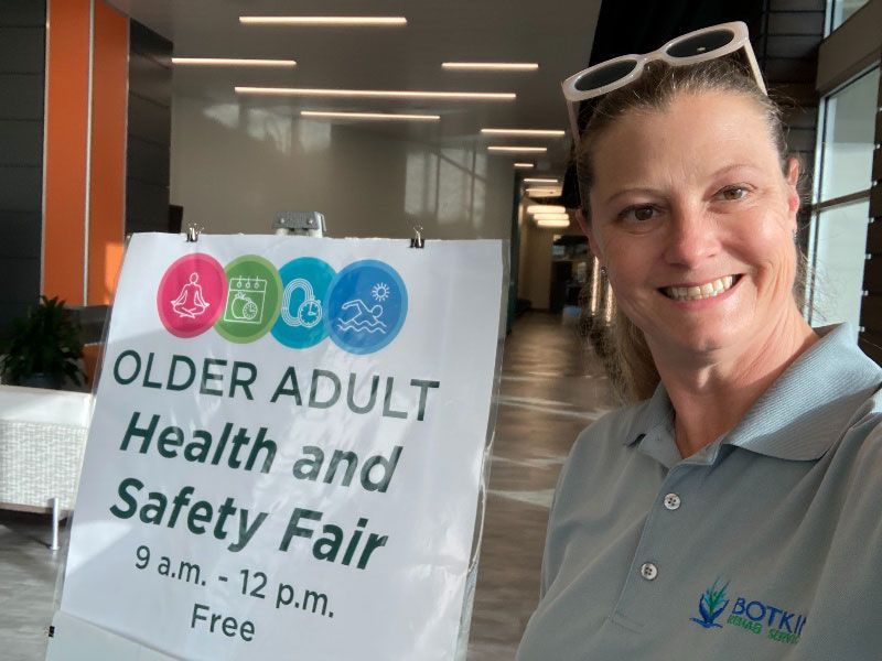 A woman is holding a sign that says older adult health and safety fair