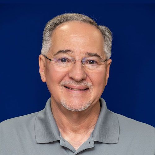 A man wearing glasses and a gray shirt is smiling for the camera.