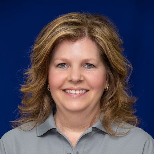 A woman is smiling for the camera while wearing a gray shirt.