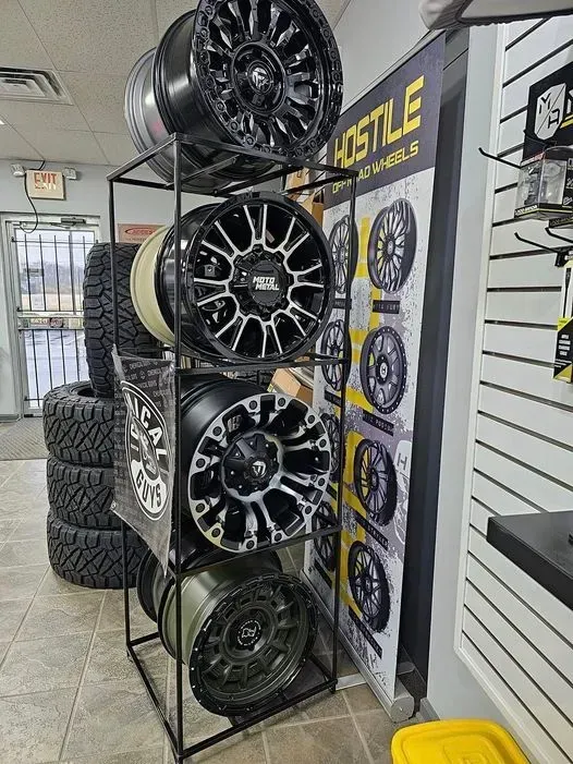 Black metal rack displaying various truck wheels inside a store, with a 