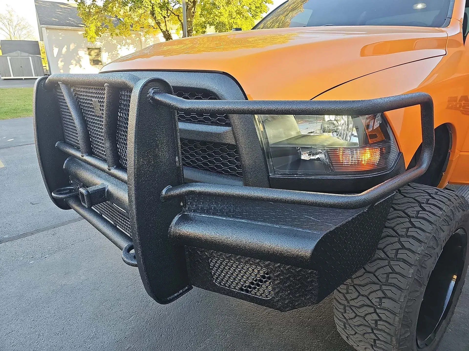 Orange truck with black, heavy-duty front bumper and grill guard.