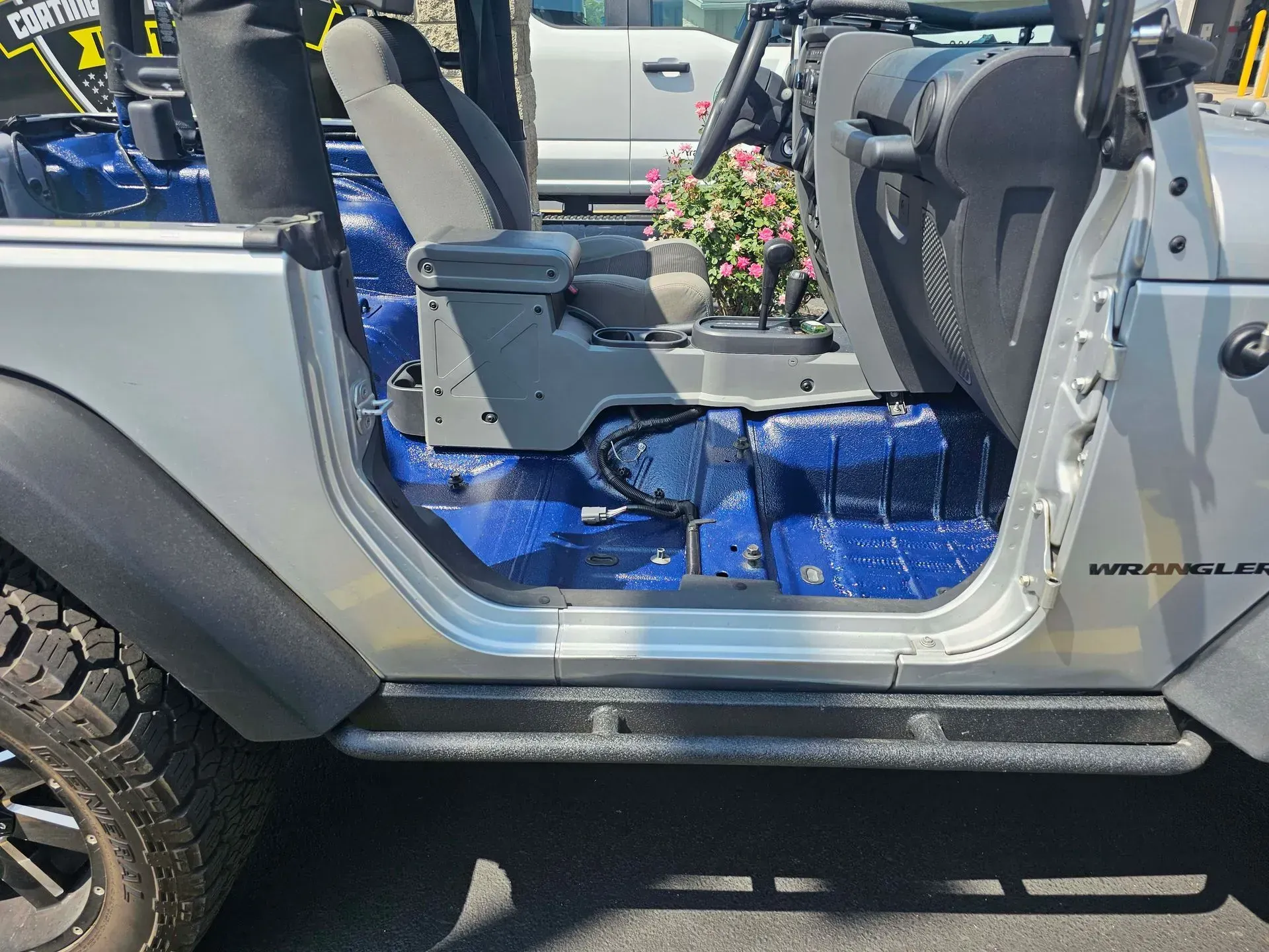 Silver Jeep Wrangler with blue painted interior, side view, open door.
