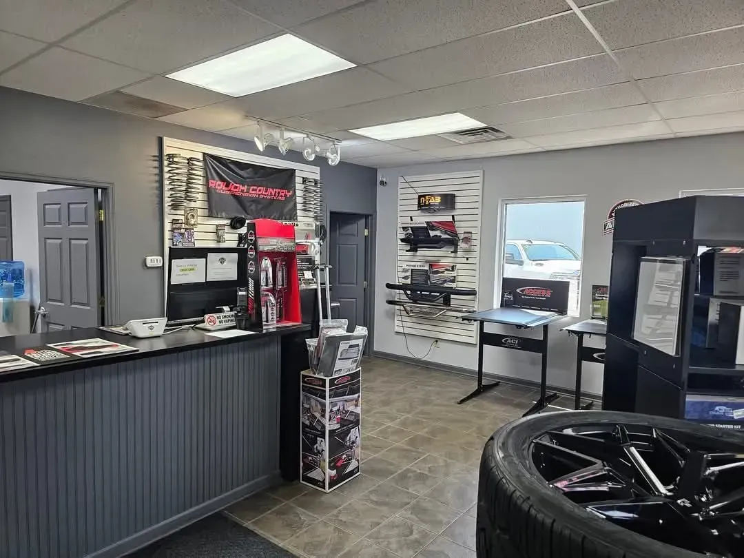 Interior of an auto shop; gray walls, black counter, display of products, a tire, and a waiting area.