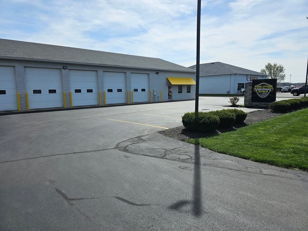Exterior of a building with garage doors, a sign, and a grassy area.